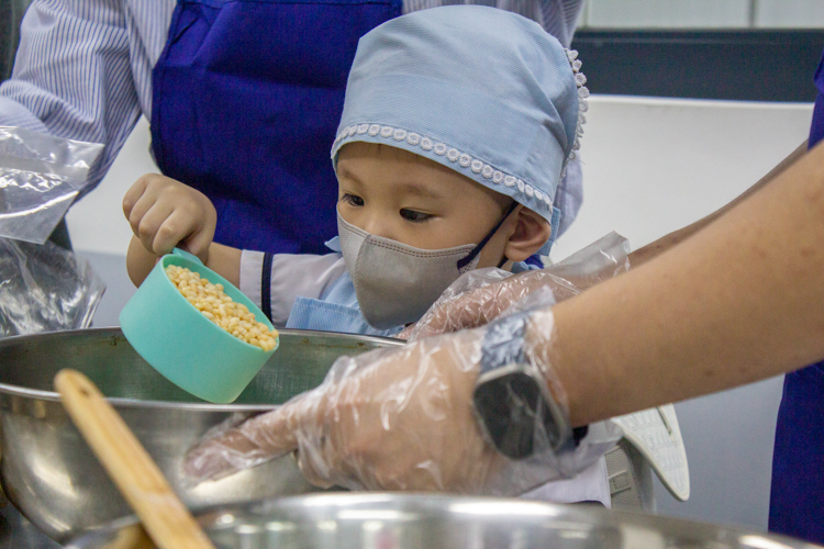 Preschool student Theo, guided by his parents, mixes ingredients in a bowl to make a chocolate bark. 【Photo by Matt Serrano】