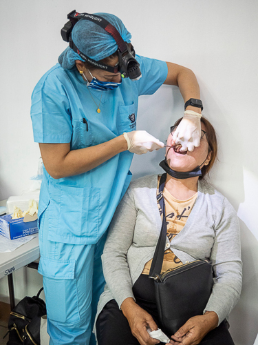 A volunteer dentist carefully conducts a tooth extraction on a patient. 【Photo by Matt Serrano】