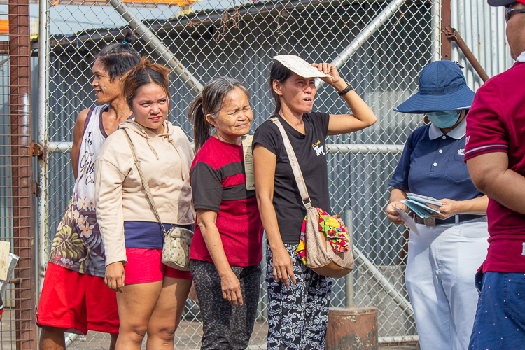 The beneficiaries endure the heat of the sun as they wait for their turn to claim the GI sheets. 【Photo by Marella Saldonido】