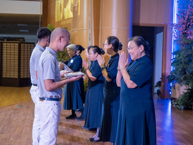 Ben Baquilod (foreground left) receives his uniform from Tzu Chi Department of Communications Head Judy Lao. 【Photo by Matt Serrano】
