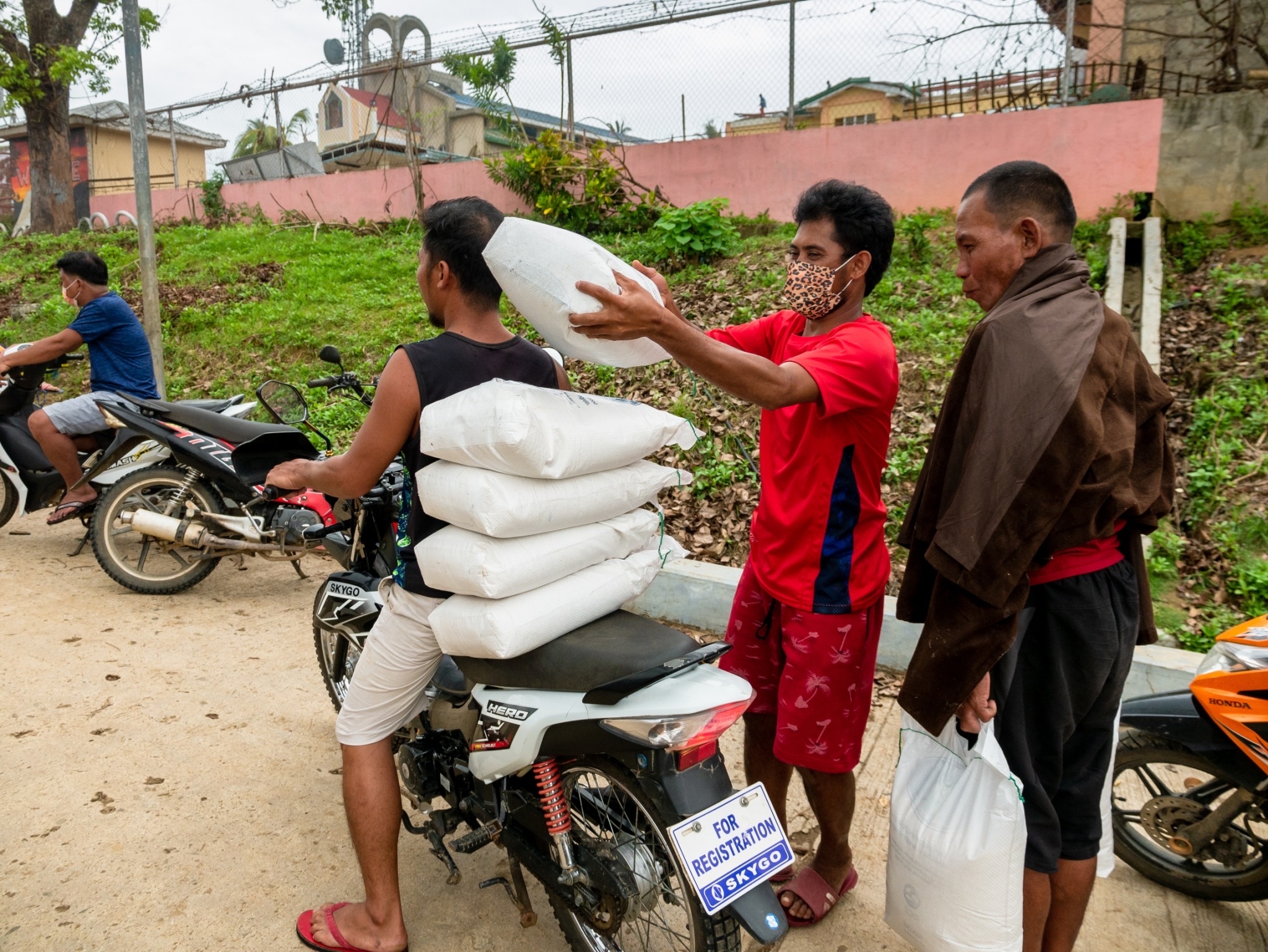 A CPG beneficiary piles sacks of 10 kg rice on the back of a motorcycle. 【Photo by Michael Sanchez】