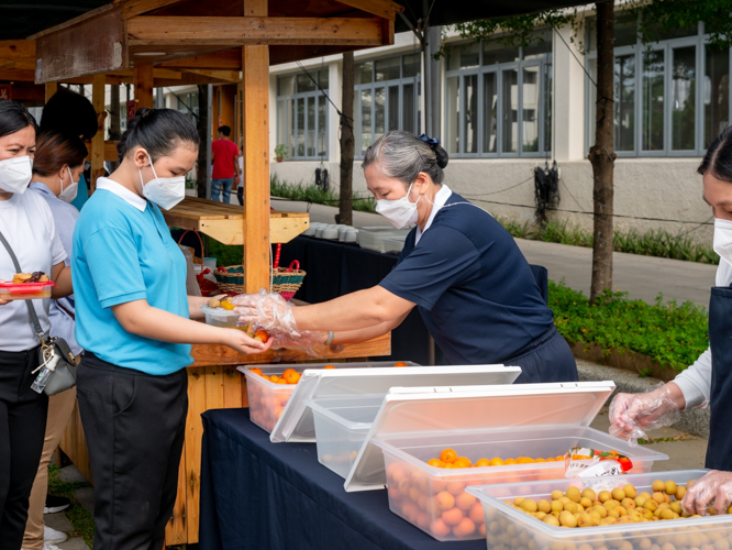 A volunteer gives a handful of fruits to a scholar. 【Photo by Daniel Lazar】