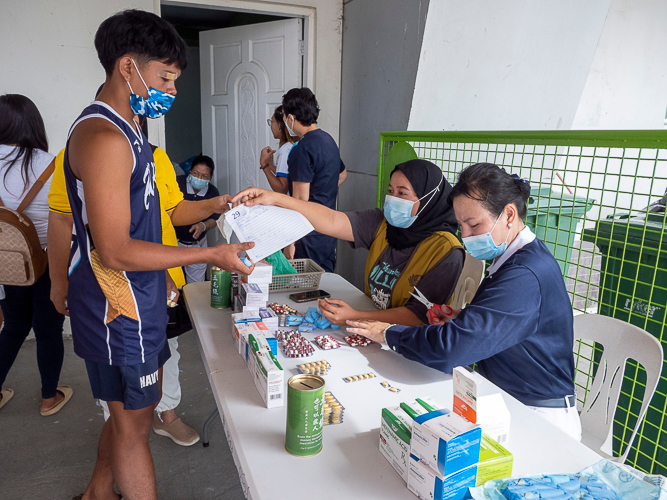 Norfahijah Lopez hands over the form to a dental patient. 【Photo by Matt Serrano】
