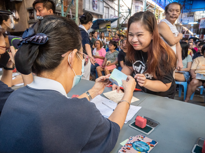 A beneficiary receives her claim stub for various relief goods from a Tzu Chi volunteer. 【Photo by Matt Serrano】