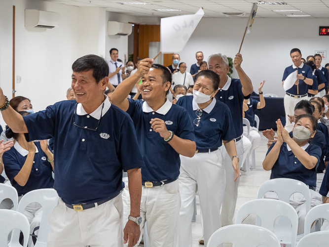 Waving flags, volunteers from Metro Manila, Bicol, Bohol Cebu, Davao, Palo, Pampanga, and Zamboanga make a lively entrance before the start of the planning session of the Tzu Chi 2023 Annual Meeting. 【Photo by Marella Saldonido】