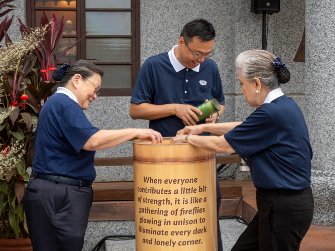 Volunteers pour in their donations into the big Tzu Chi coin bank. 【Photo by Matt Serrano】
