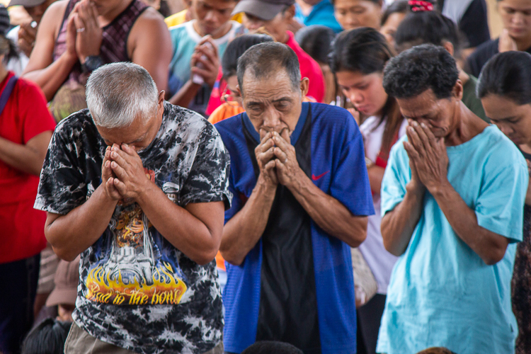 In a solemn moment, residents of Brgy. Bayho join Tzu Chi volunteers in prayer. 【Photo by Matt Serrano】