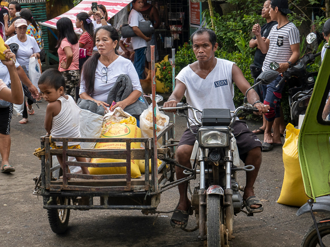 A family transports their relief items home using a motorcycle sidecar. 【Photo by Matt Serrano】
