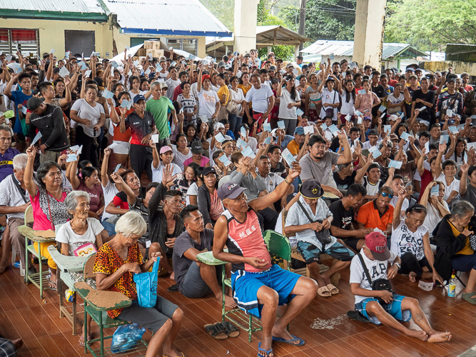 Residents of Brgy. Bayho raise their stubs in eager anticipation as they await the distribution of relief goods【Photo by Matt Serrano】
