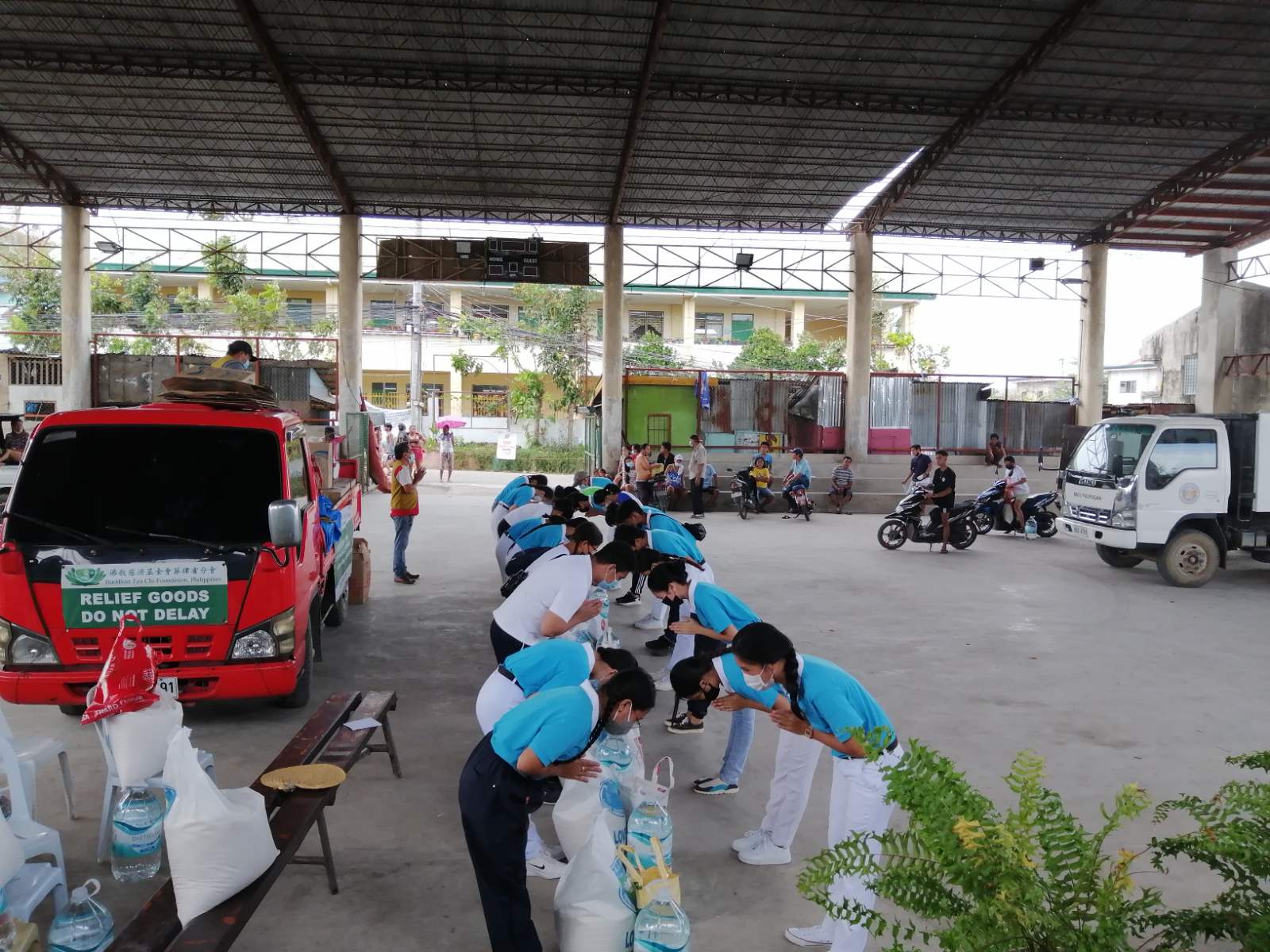 Tzu Chi scholars from Barangay Pulpogan bow in gratitude for the 20kg sacks of Taiwan rice, 10 liters of potable water, and grocery items they received. 