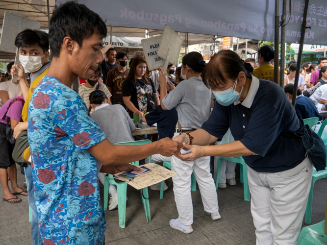 A volunteer receives a fire beneficiary’s stub so he can claim aid. 【Photo by Matt Serrano】