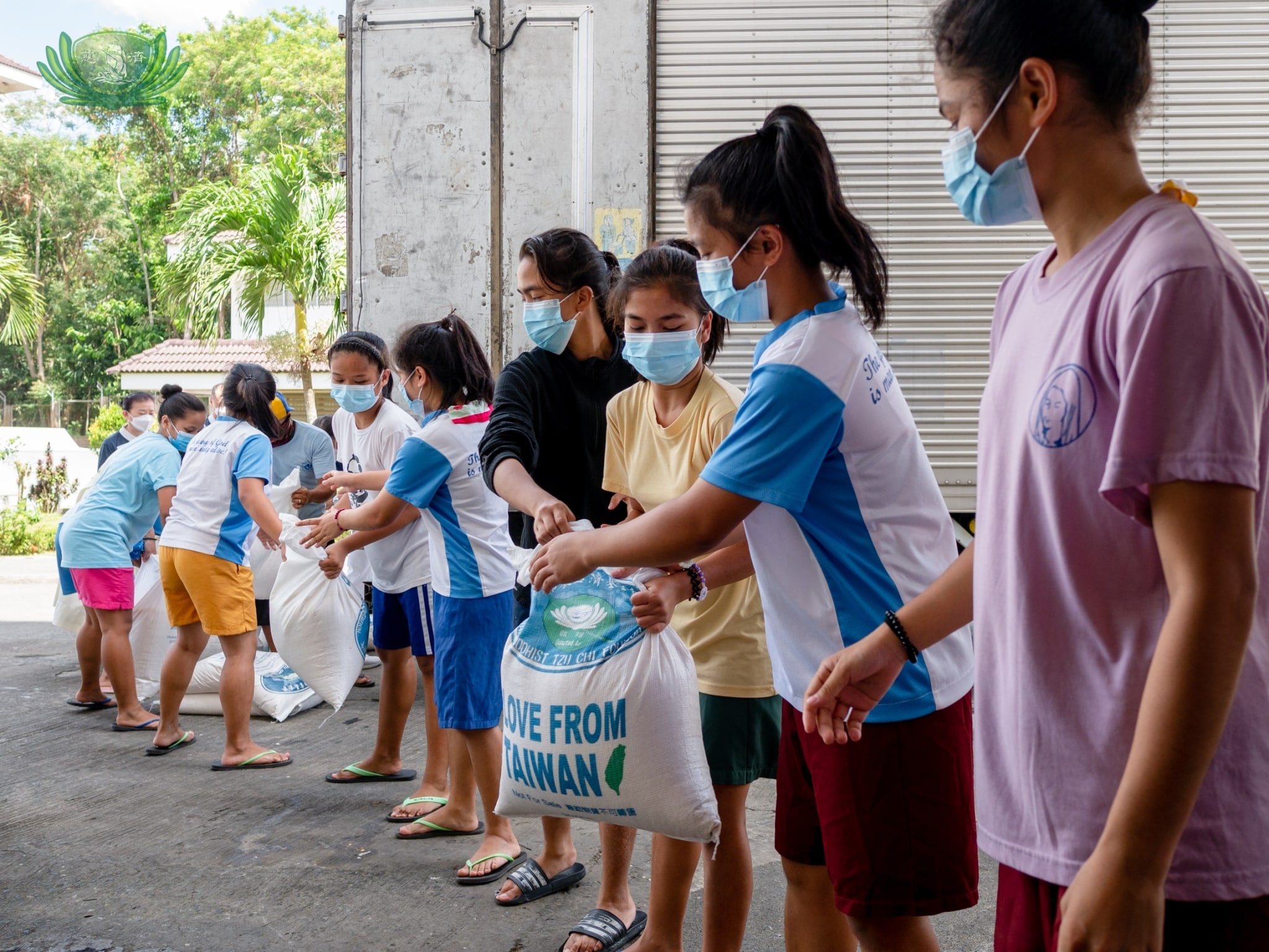 he students at Girlstown form a line to pass the sacks of rice donated by Tzu Chi Foundation.【Photo by Daniel Lazar】