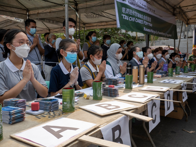 Volunteers at the registration table take a moment to pray for the blessings of survival and relief following a May 15 blaze. 【Photo by Matt Serrano】