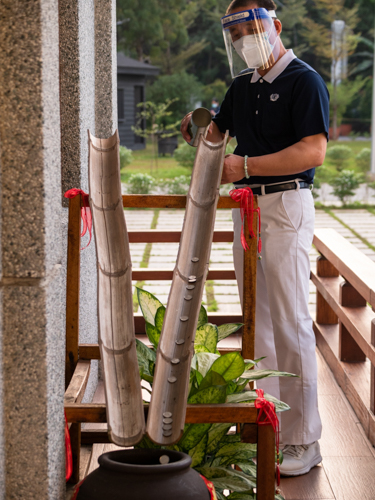 A volunteer empties the contents of a Tzu Chi coin bank into a bamboo slide. 【Photo by Daniel Lazar】