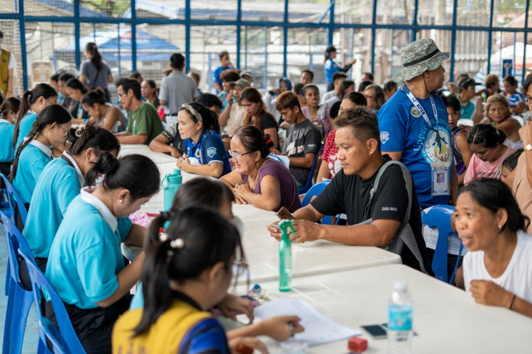 Tzu Chi scholars (left) assist in the issuing of claim stubs to beneficiaries.