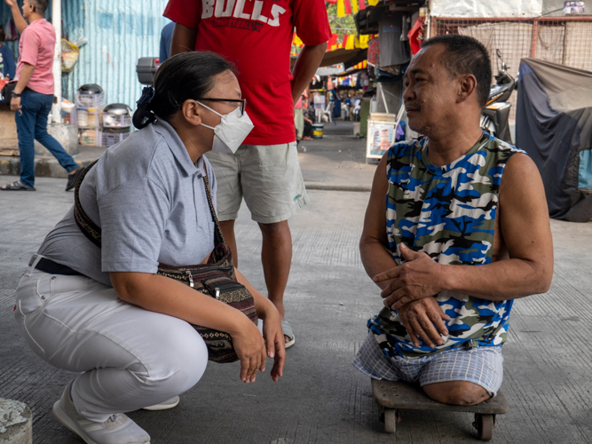 Oroquieta resident Sandy Sebunga (right) chats with Tzu Chi Charity Department Head Tina Pasion about seeking medical assistance. Sandy became a double amputee when he was hit by a garbage truck in 1996. 【Photo by Matt Serrano】