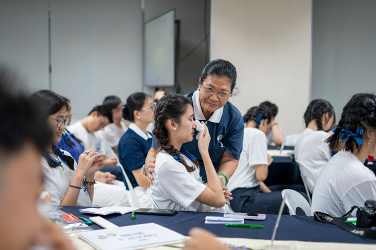 A volunteer comforts a participant when she is moved to tears during a talk on filial piety. 