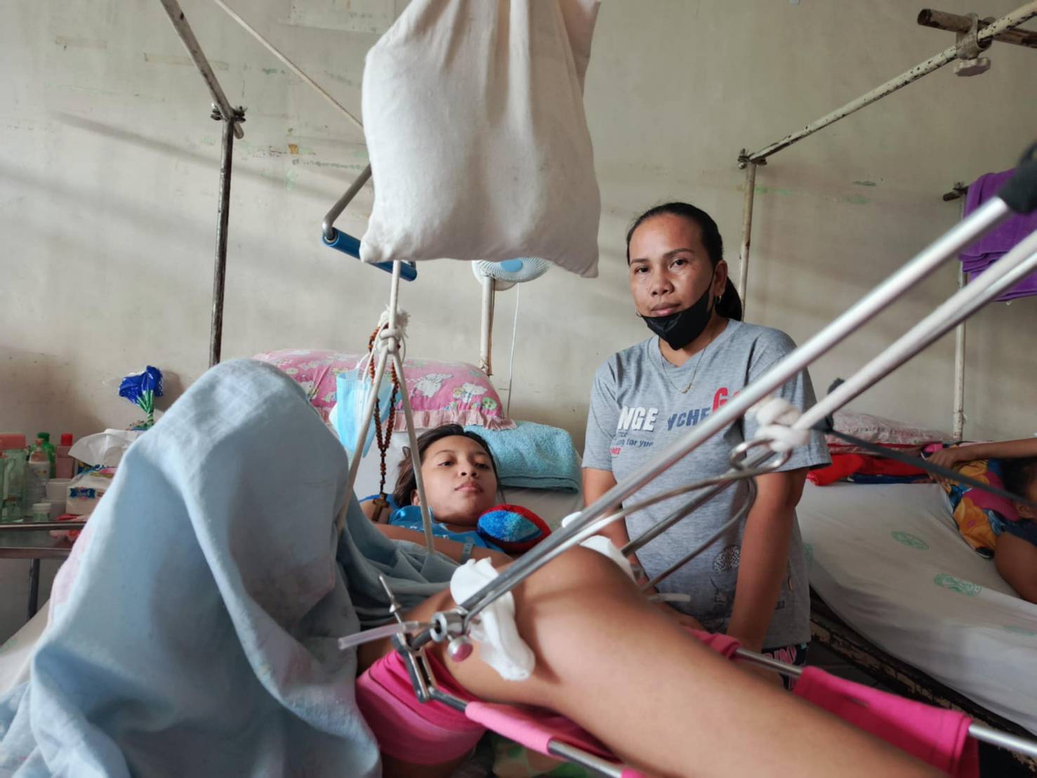 At the Philippine Orthopedic Center, Lucy Tayongana (right) watches over her daughter Liezel Sandocal, who broke her left thigh when a vehicle hit the motorcycle she was riding. (Photo: Julie Collado)