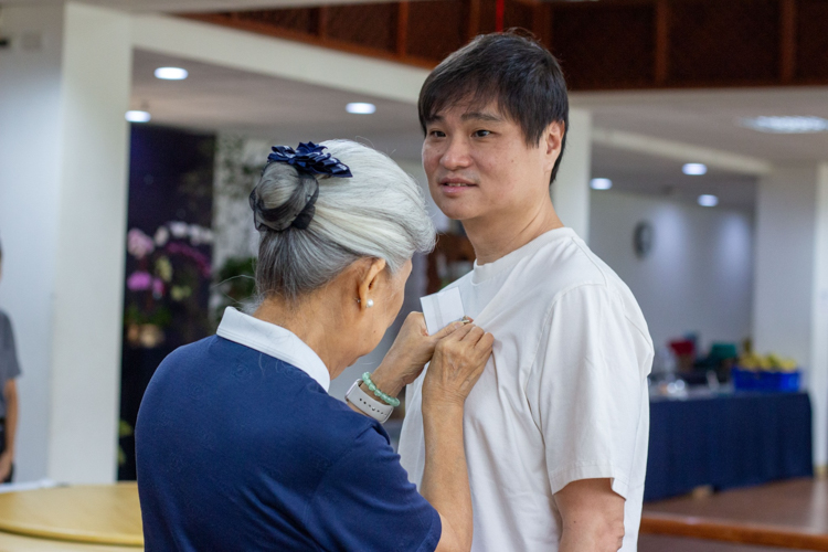 Tzu Chi Philippines’ first CEO Linda Chua pins a name tag on her grandson Ken before the start of the New Volunteers Camp. 