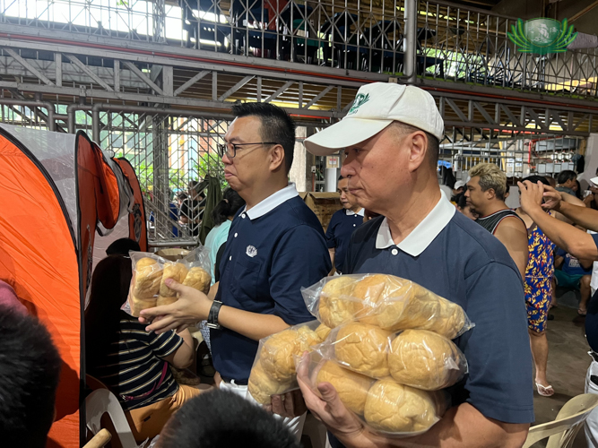 Tzu Chi volunteers Wilson Hung (left) and Luis Diamante bring bread from the Tzu Chi Bakery to families temporarily residing at the covered court of the University of Santo Tomas-Angelicum College in Sto. Domingo, Quezon City.