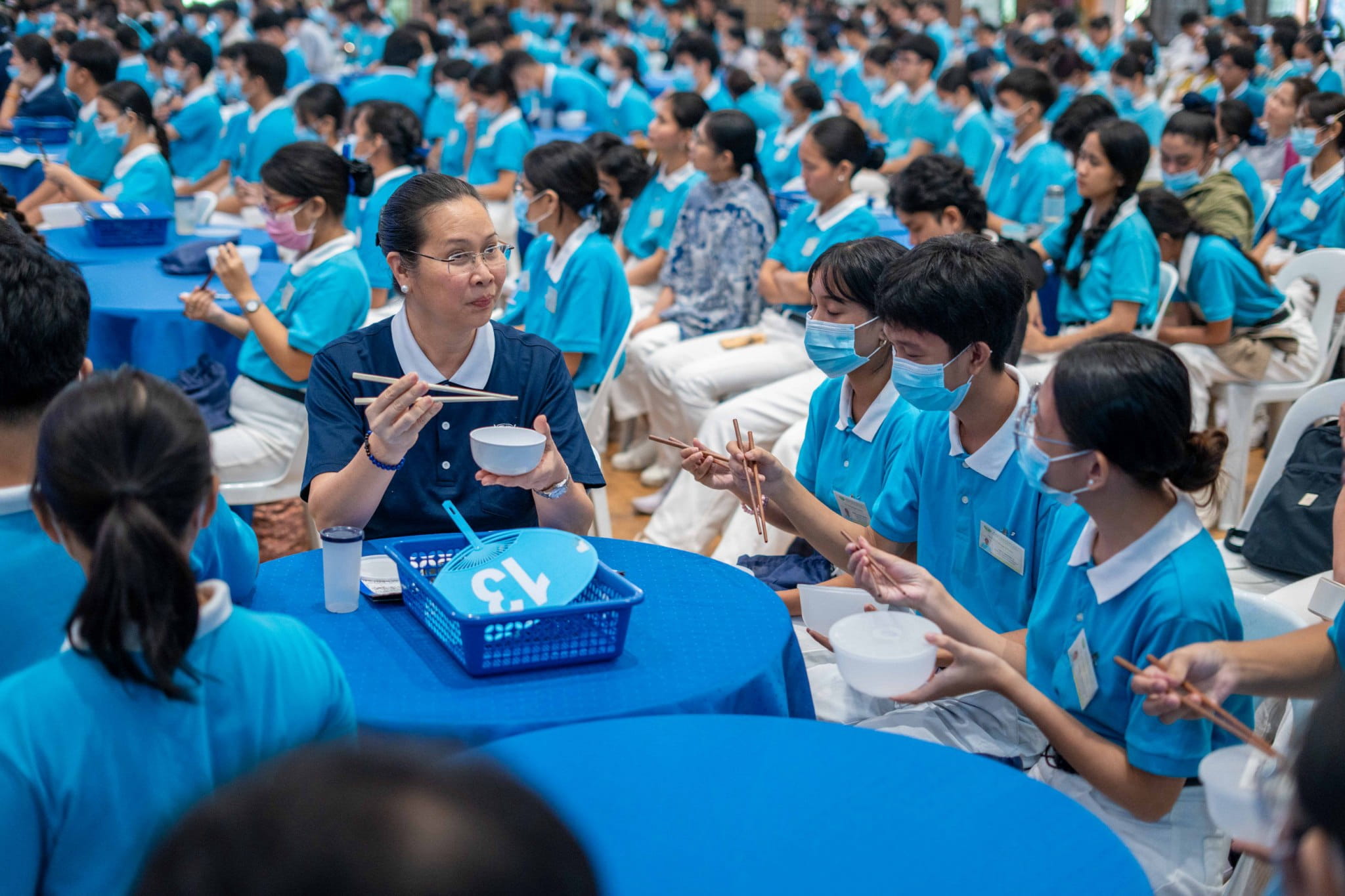 Tzu Chi volunteer Joy Gatdula joins scholars in using chopsticks.