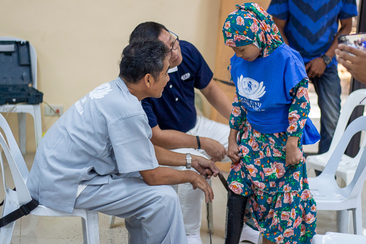 Volunteer prosthetic technician Jose Waldemar Rico (left) and Tzu Chi Zamboanga Liaison Officer Dr. Anton Mari Lim (center) help a young patient with her prosthesis.