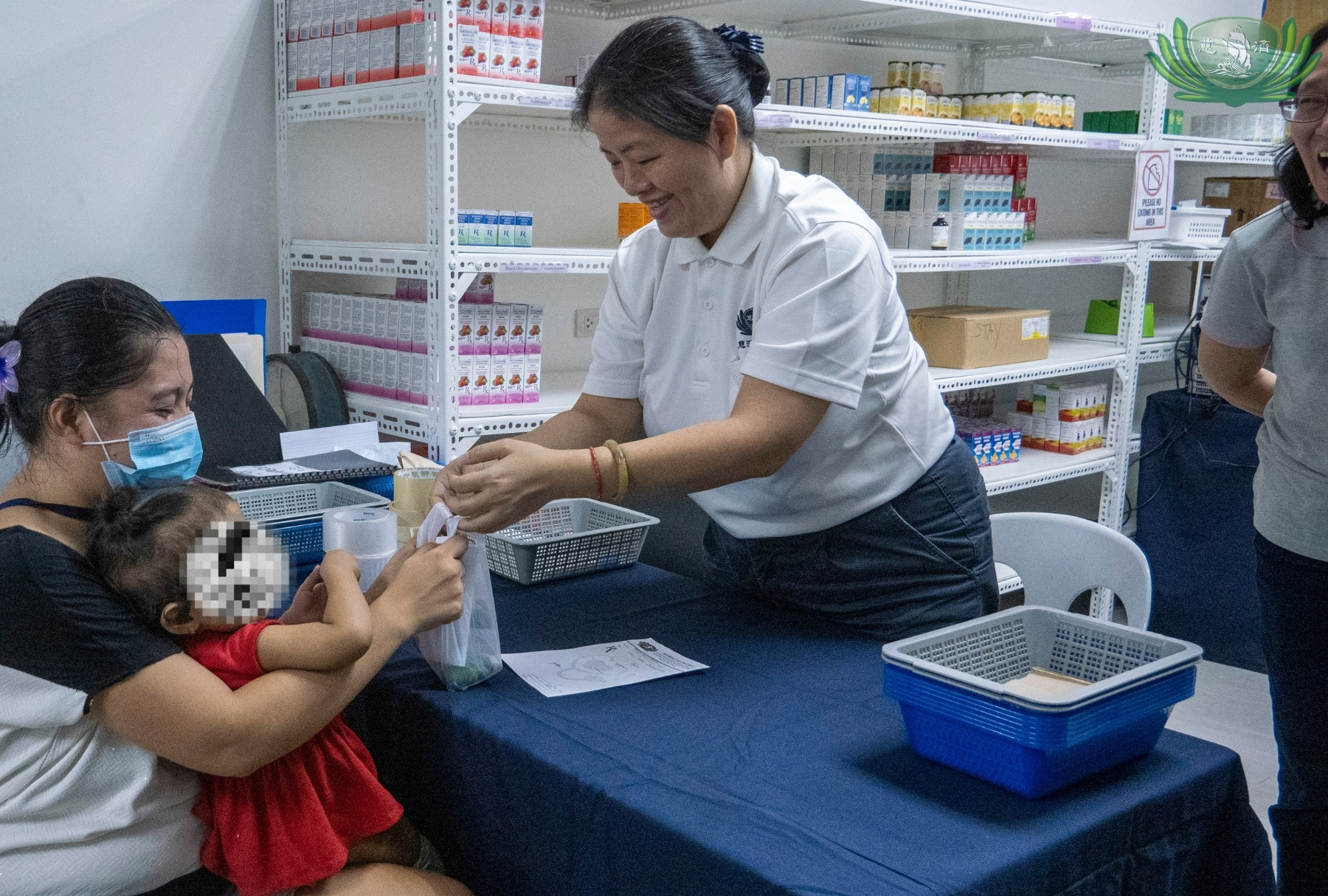 Tzu Chi volunteer and pharmacist Goldie Ngo gives medicines to a parent for her young daughter after a pediatric consultation.