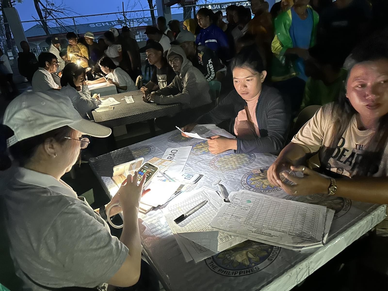 When strong rains and a brownout hit Panganiban, residents and Tzu Chi volunteers relied on cellphone flashlights to facilitate the release of claim stubs. 