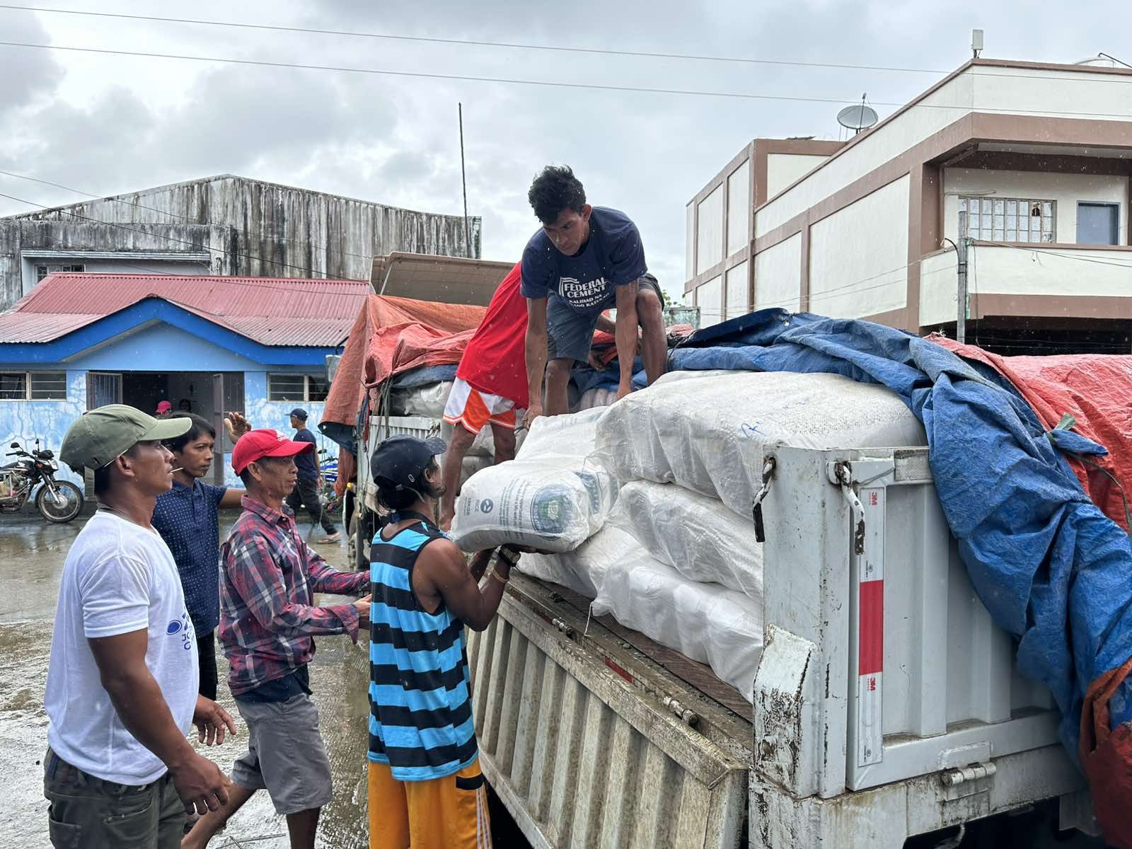 Local volunteers help unload sacks of rice for distribution in Viga. 