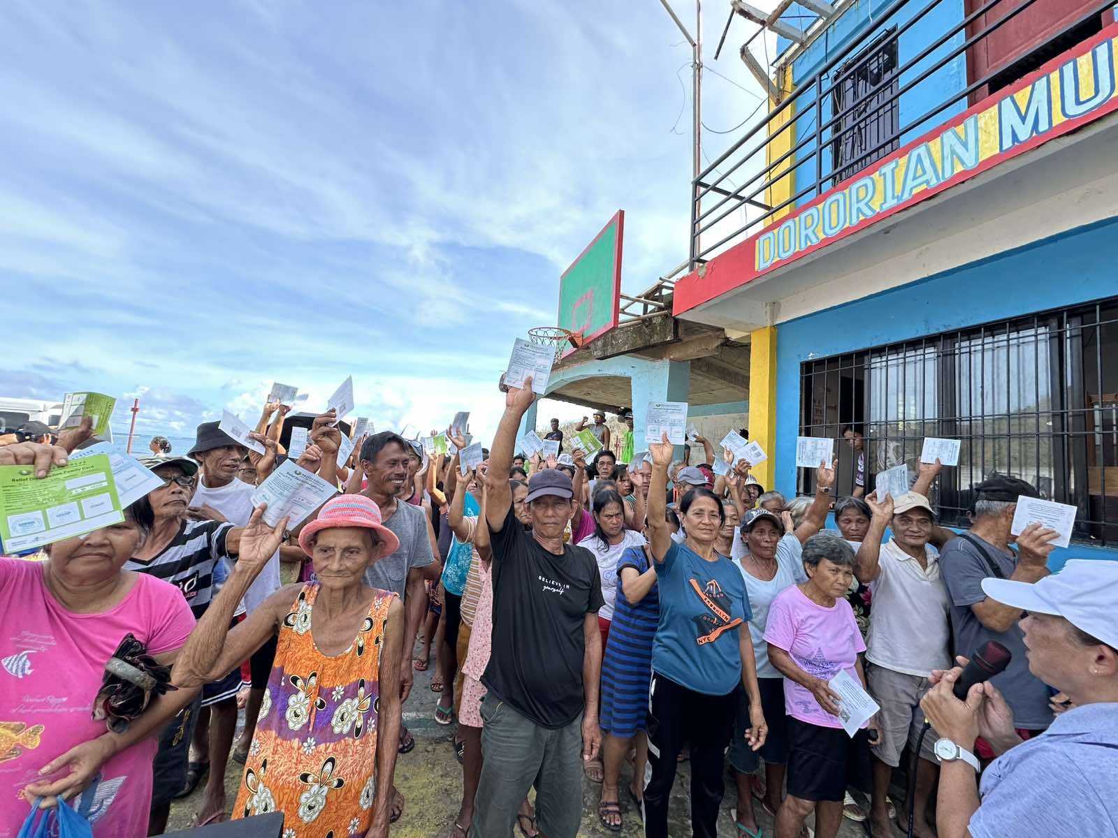 In Gigmoto, residents wave their claim stubs in the air before receiving their 10-kg sack of rice.