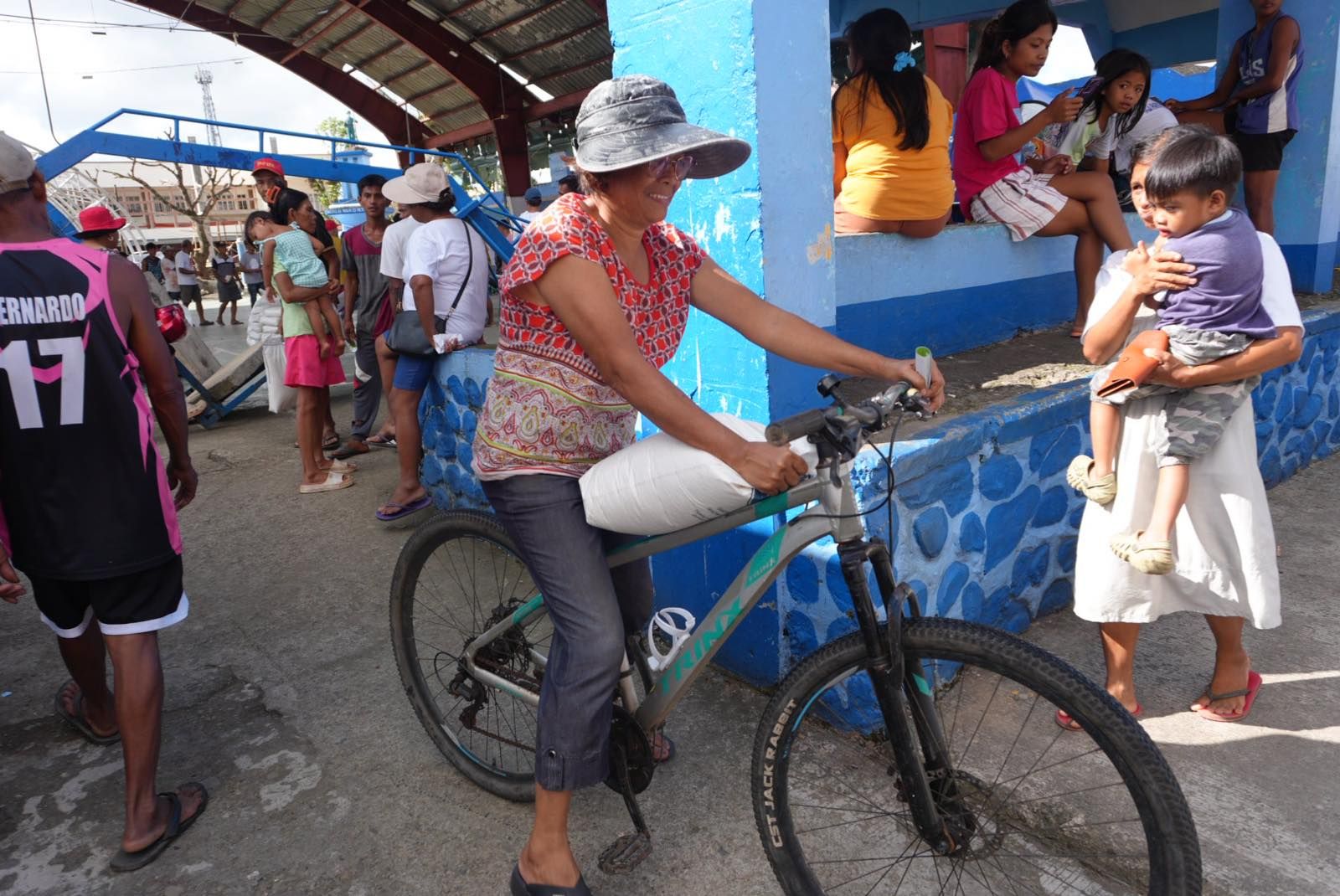 In Viga, a woman balances her 10-kg sack of rice on the frame of her bike. 