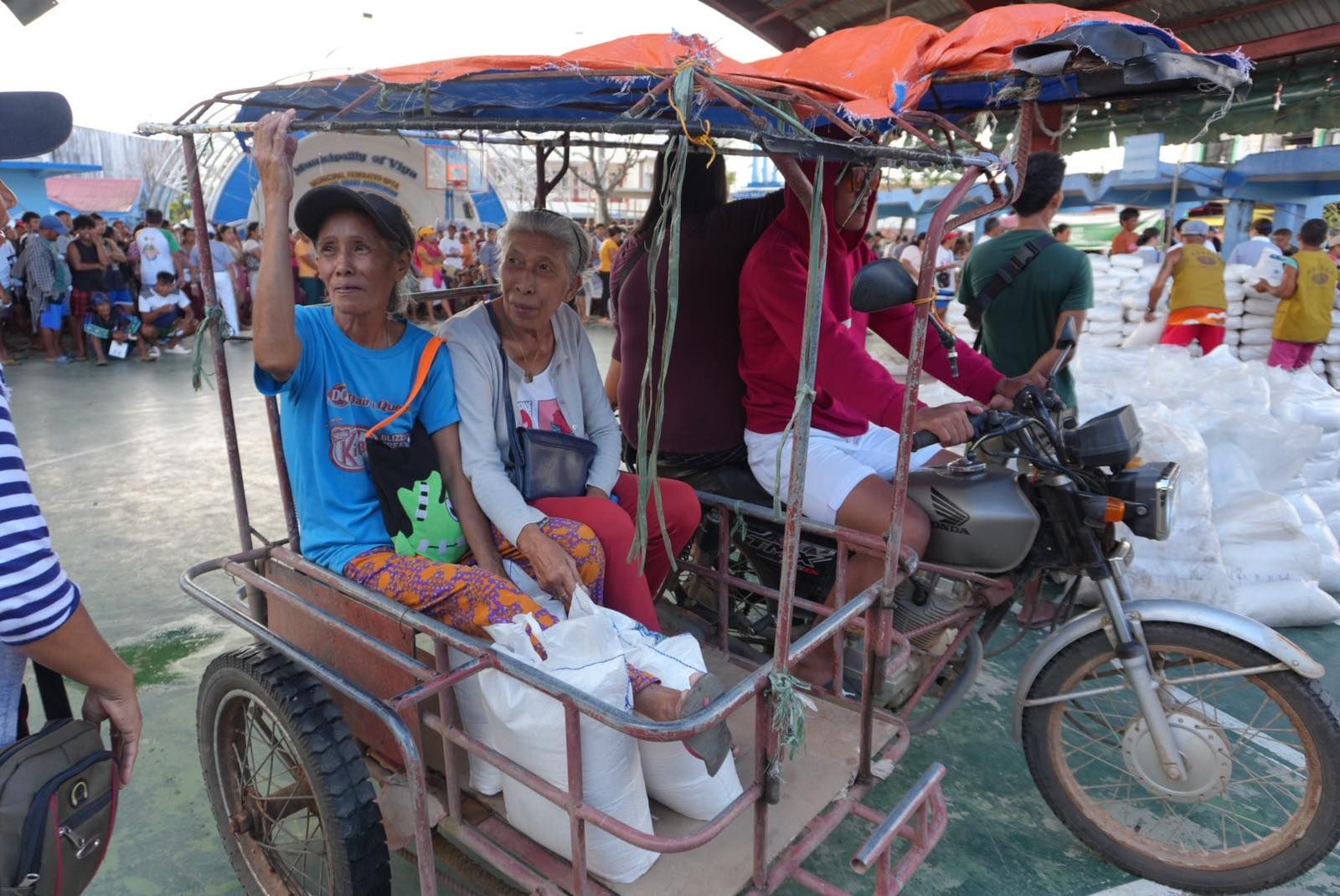 Seniors take a tricycle to bring them and their sacks of rice home. 