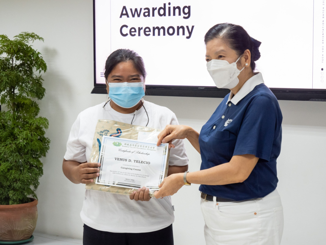 Venus Telecio (left) receives her certificate of scholarship for a caregiving course from Tzu Chi Education Committee Head Rosa So.