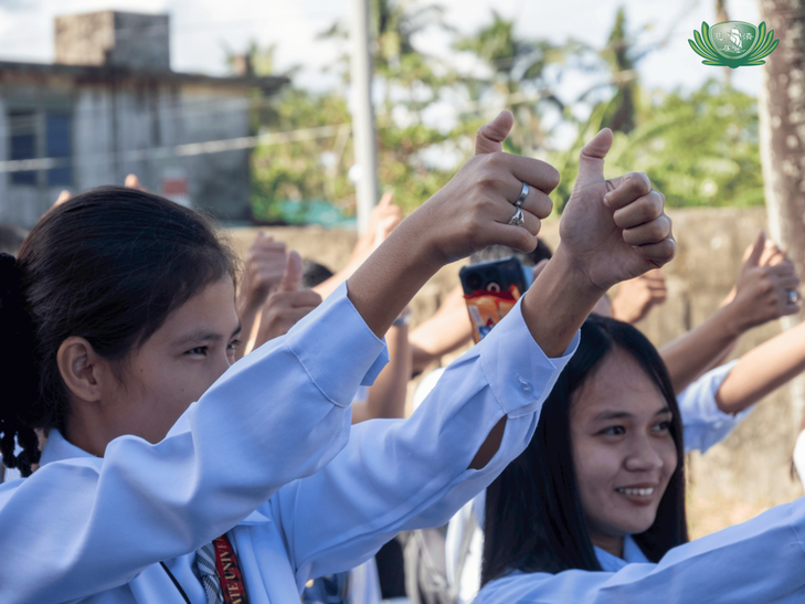 Students learn the Tzu Chi hand sign for bowing in gratitude. 