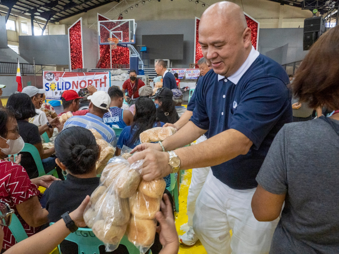 A Tzu Chi volunteer helps in distributing bread during their visit in Aparri, Cagayan.