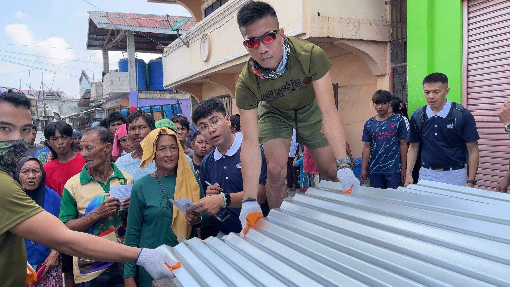 Members of the Philippine Navy Marines assist in the distribution of galvanized iron sheets. 