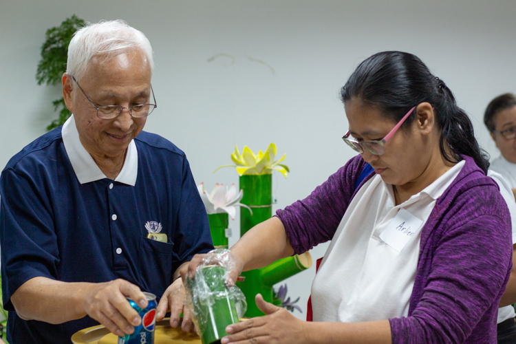 Tzu Chi volunteer James Cheng assists TechVoc alumni as they turn over the contents of their coin bank. The donated money will be pooled together to help future batches of TechVoc scholars.