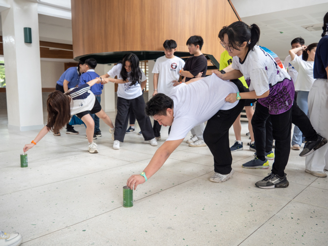 Concentration is key as participants carefully drop coins into Tzu Chi coin banks during the Coin Can Relay Race at Unity Hall.