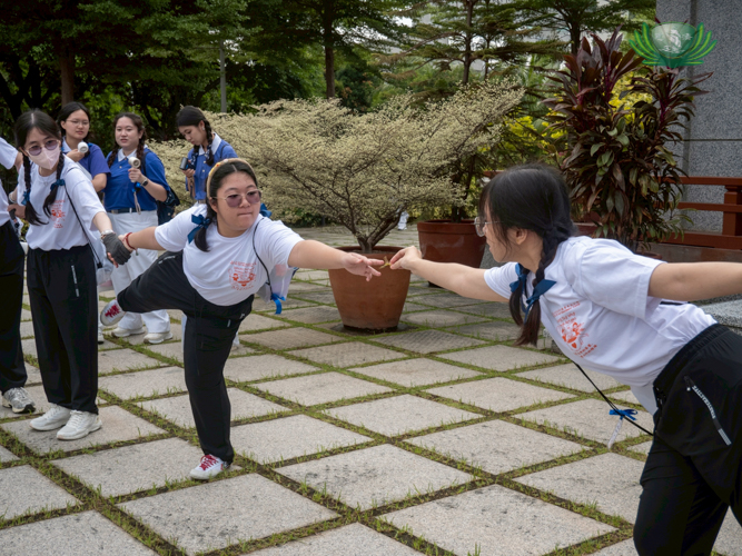 In one outdoor game, campers reach out to pass and receive a leaf without falling.