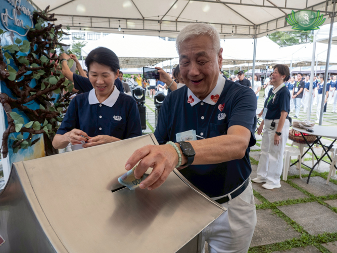 Tzu Chi Foundation Philippines CEO Henry Yuñez drops his donation for the Tzu Chi General Hospital in a metal container, and Tzu Chi Foundation Philippines Deputy CEO Woon Ng (left) follows suit.