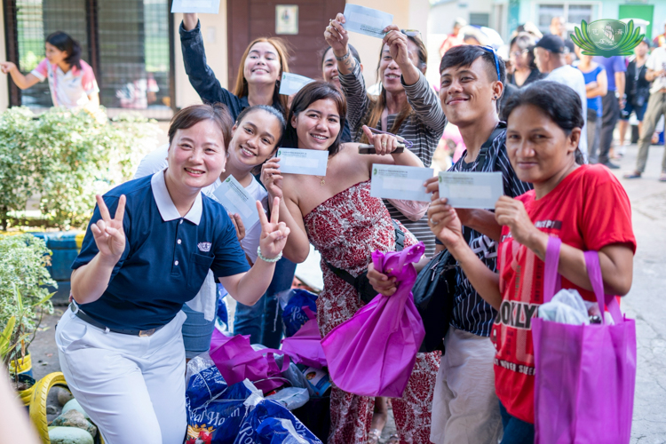 Beneficiaries pose for photos with Tzu Chi volunteer Sharon Sy (first from left), who led the relief operations in Singcang-Airport.