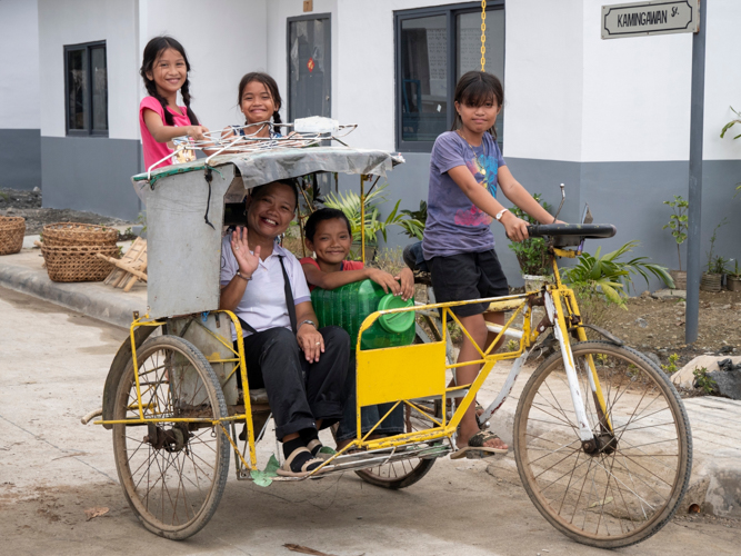 Residents of the village explore their new community by tricycle.