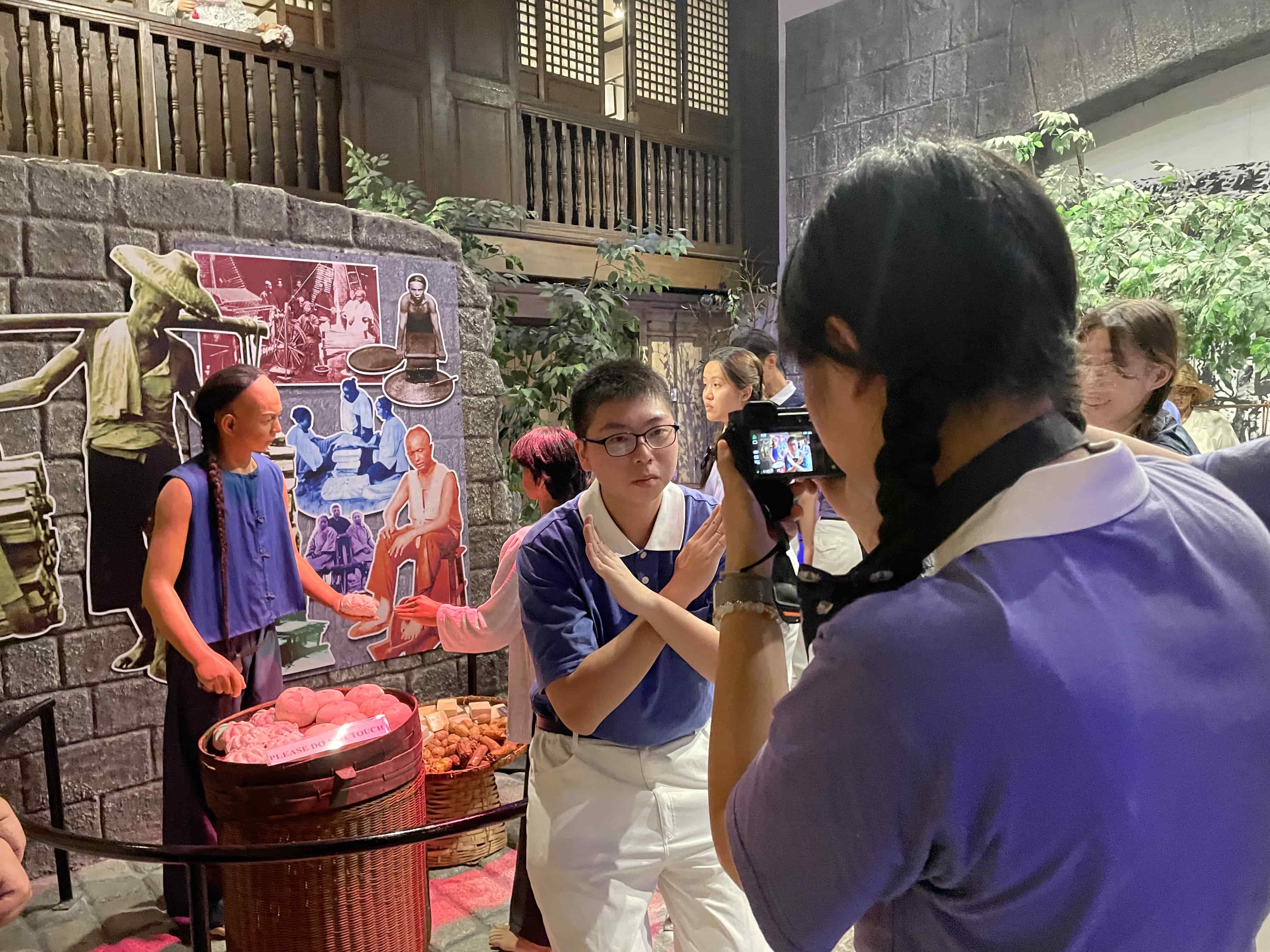 Posing next to a life-size diorama of an early Chinese merchant