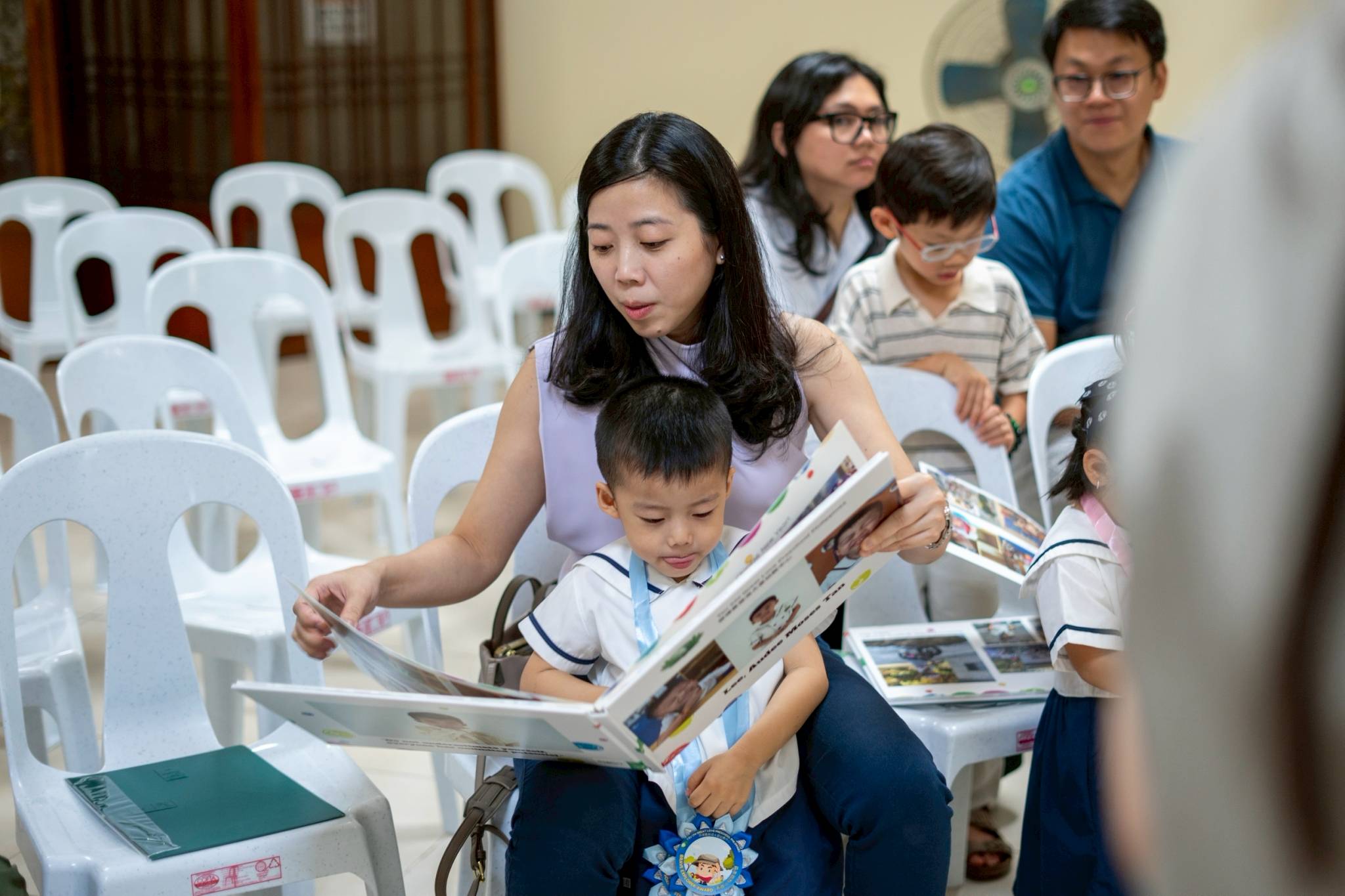 While waiting for the program to commence, parents look through their child’s photo album to see their journey. 