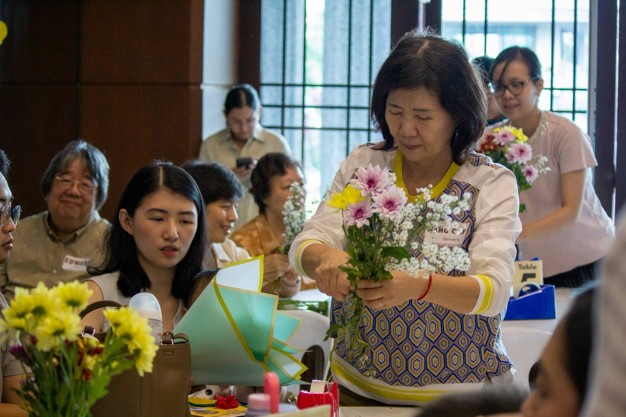 Grandparents happily join in on the flower-making activity with their family.
