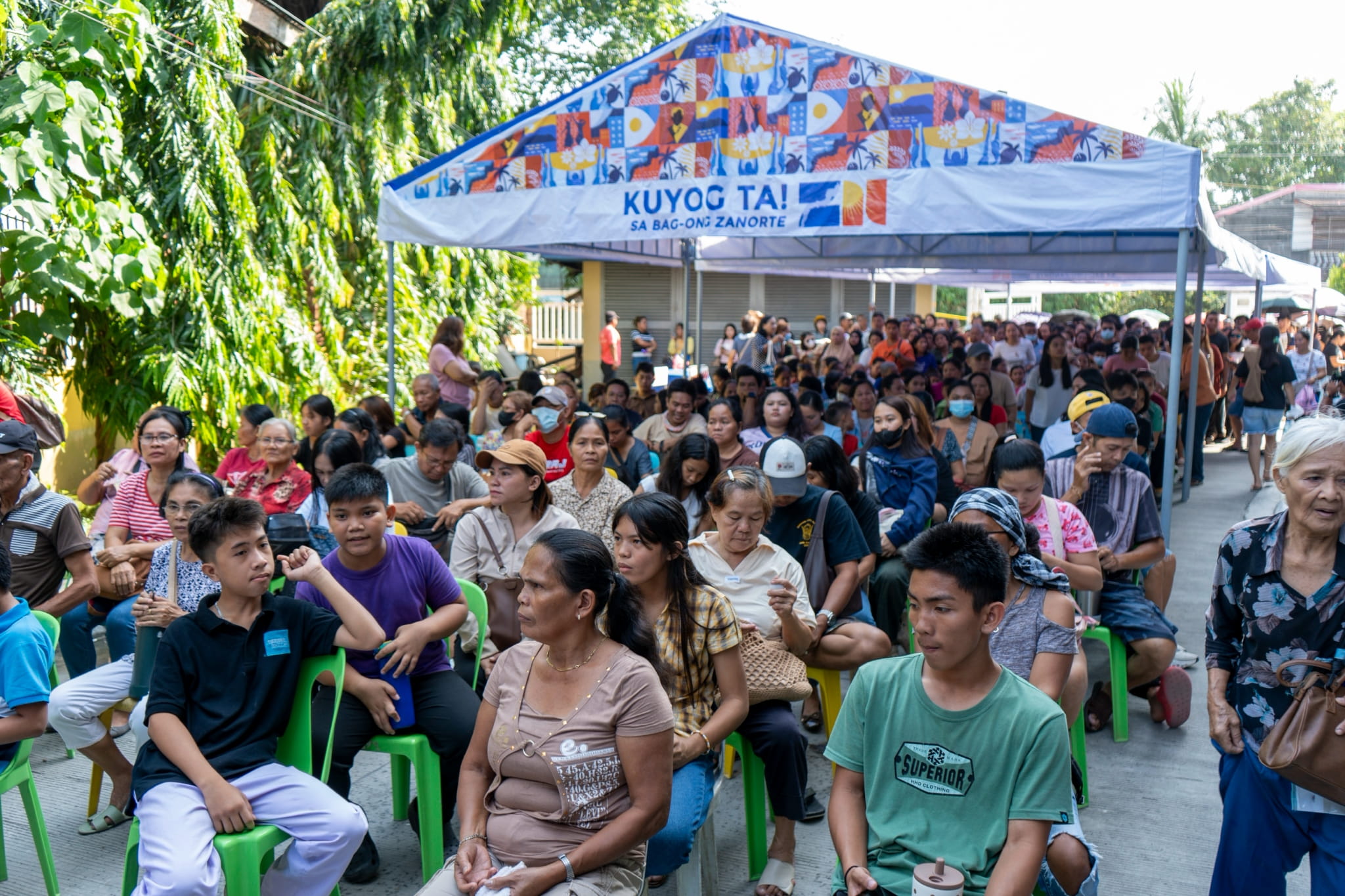 A long queue of patients forms outside the venue as registration begins.
