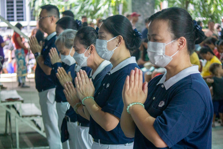 Tzu Chi volunteers lead a prayer of gratitude before receiving the relief items.