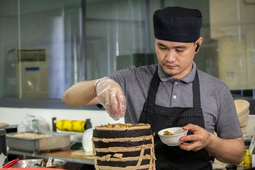 Adrian Neil Ang carefully layers the chocolate cake of Tzu Chi’s flag-inspired 30th anniversary cake. 