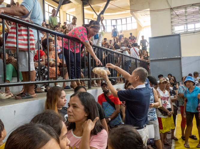 A Tzu Chi volunteer helps in distributing bread during their visit in Aparri, Cagayan.