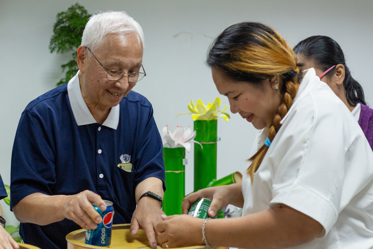 Tzu Chi volunteer James Cheng assists TechVoc alumni as they turn over the contents of their coin bank. The donated money will be pooled together to help future batches of TechVoc scholars.